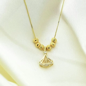 Elegant gold necklace with zircon fan pendant and frosted beads on silk background