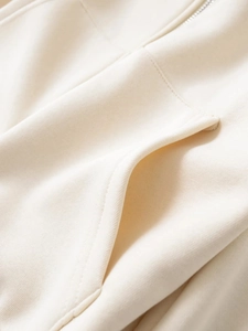 Detailed close-up of cream hoodie featuring zipper and stitching on soft knitted fabric