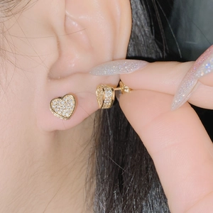 Close-up of 18k gold plated heart stud earrings with cubic zirconia on a model's ear