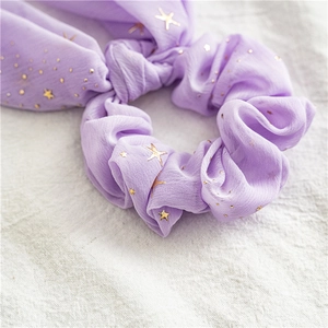 Macro detail of purple chiffon scrunchie featuring gold foil stars and moon patterns
