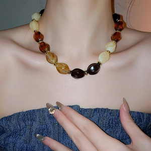 Detail of amber and cream chunky resin bead necklace worn by a model in soft lighting