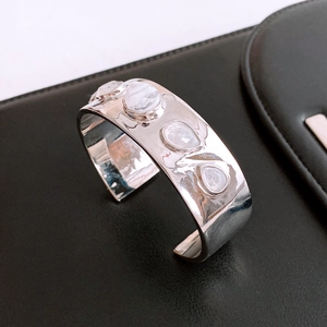 Macro detail of silver cuff bracelet featuring polished finish and inlaid white stones