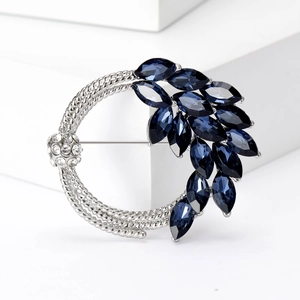 Macro detail of silver wheat ear brooch with deep blue marquise crystals and round gems