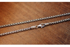 Detail of silver titanium steel curb chain showing textured links and lobster clasp