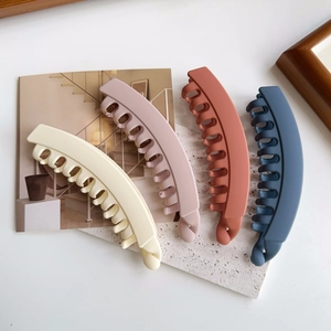 Matte banana hair clips in four colors on a textured stone plate for thick hair