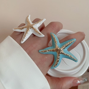 Detail of starfish rings with blue and white enamel drip on a model's hand