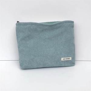 Detail view of light blue corduroy makeup bag with textured stripes and May Rabbit label