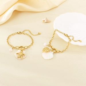 Detail view of gold ocean-themed bracelet with sea turtle, shell charms and pearls