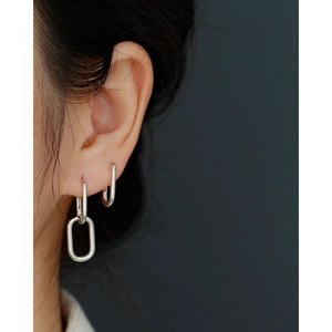 Close-up of geometric oval S925 silver earrings worn by a model with a metallic finish