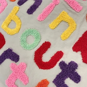 Detail of colorful chenille letter embroidery on large canvas tote bag fabric