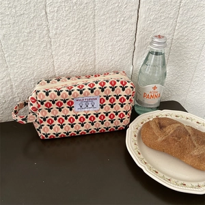 Macro d'une trousse à maquillage en velours côtelé fleuri sur une table en bois