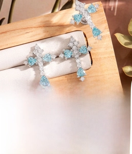 Detail showing silver cross cartilage stud with blue heart zircon on wooden background