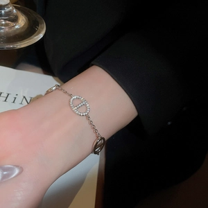 Detailed view of silver oval link bracelet with micro-pave zircons on a woman's wrist