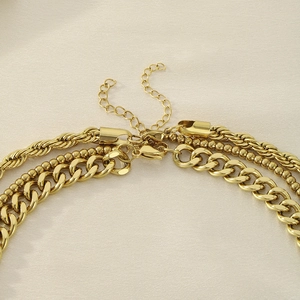 Close-up of gold layered chain necklace featuring lobster clasps and extension links