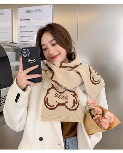 Detailed knit texture of long scarf featuring bear motifs and BEAR typography
