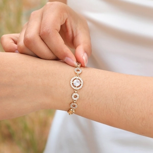 Macro shot of gold-plated chain bracelet with zircon pavé ring charm on female wrist