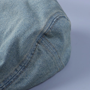 Detailed close-up of light blue denim fabric with contrast orange double stitching accents