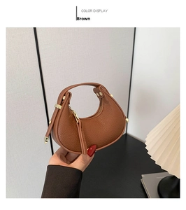 Detail of a brown crescent bag showing lychee leather texture and gold metal hardware