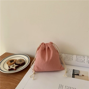 Close-up of pink drawstring storage pouch with textured fabric and soft cotton ropes