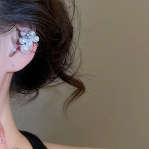 Gros plan d'un ear cuff fleur en perles et zircon porté sur le cartilage d'un mannequin