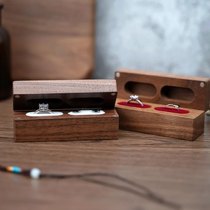 Detail of walnut wood double ring box with soft velvet lining on wooden surface