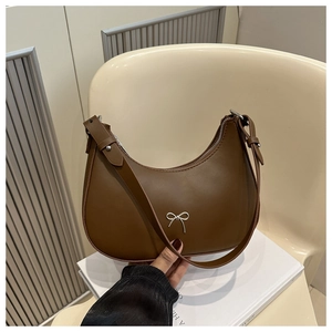 Detail shot of the silver bow accent on a brown leather crescent shoulder bag
