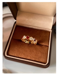 Macro detail of gold plated heart ring with red enamel and zircon stones in a jewelry box