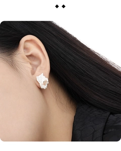 Macro detail of asymmetric silver earring with textured finish and champagne gemstone