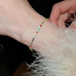 Close-up of a gold rainbow bracelet with colorful round gemstones on a model wrist