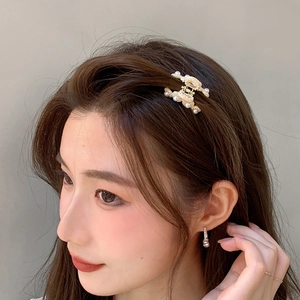 French palace style golden hair claw with pearls and matching earrings on model