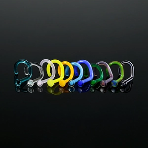 Detailed view of colorful L-shaped glass nose studs on a professional black reflective surface