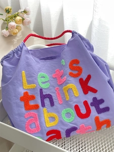 Detail of chenille embroidery text and durable rope handles on a purple canvas tote bag
