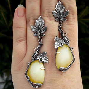 Detailed view of silver vine leaf earrings with pear-shaped cat eye stone in hand