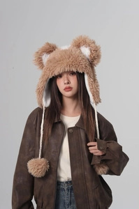 Detailed texture of fluffy light brown faux fur earflap hat with cute bear ears and poms