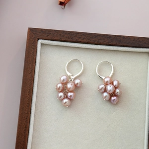 Detail shot of pink freshwater pearl grape cluster earrings in a wooden jewelry box