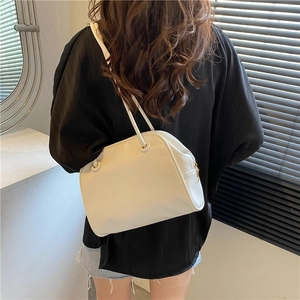 Minimalist white PU leather tote bag shown on model in a soft lit indoor setting
