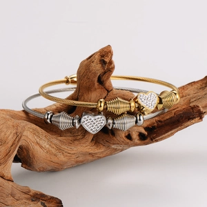 Gold and silver heart cable bracelets with rhinestones displayed on rustic wood