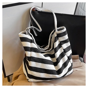 Detail of a large striped canvas tote bag resting on a dark chair with a beige coat
