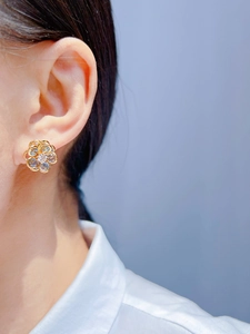 Close-up of elegant gold flower earrings with crystals on female model ear
