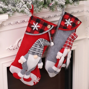 Pair of red and grey Christmas stockings with faceless gnome dolls on a fireplace