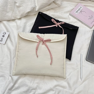 Vista dettagliata di custodie per laptop trapuntate con fiocchi rosa sul letto