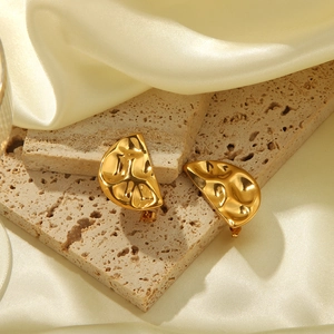 Gros plan de boucles d'oreilles demi-cercles dorées avec texture métallique martelée