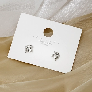 Macro view of silver dolphin earrings with clear crystals on a white jewelry card