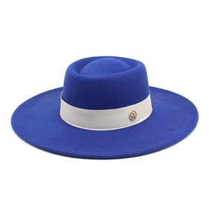 Detail of Klein blue wool fedora with wide beige ribbon and gold M letter metal badge