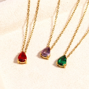 Detailed shot of three gold necklaces with red, purple, and green teardrop zircon pendants