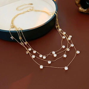 Détail du collier multicouche doré avec zircons sur un plateau vert élégant