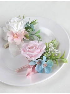 Detailed view of handmade white and pink rose corsages with ribbon wrapped stems