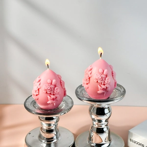 Detail of pink egg-shaped candles with rose floral relief on silver candle holders