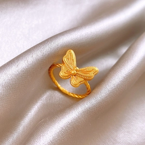Detailed close-up of a vintage golden butterfly ring resting on premium silk fabric