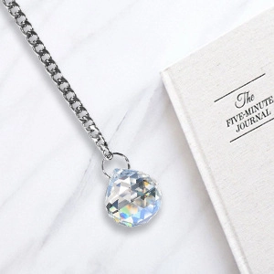Detailed view of multifaceted crystal ball pendant with silver chain on marble
